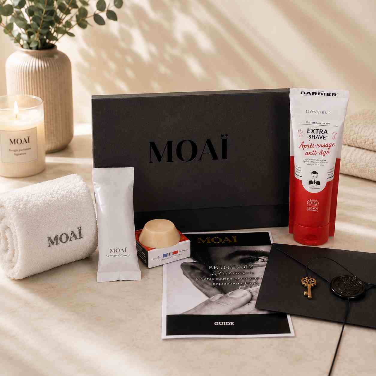 Coffret de soins homme MOAÏ présenté avec des produits de rasage et de soin du visage, une serviette brodée, un savon artisanal et un guide de routine. Ensemble prêt à offrir pour une routine masculine simple et efficace.