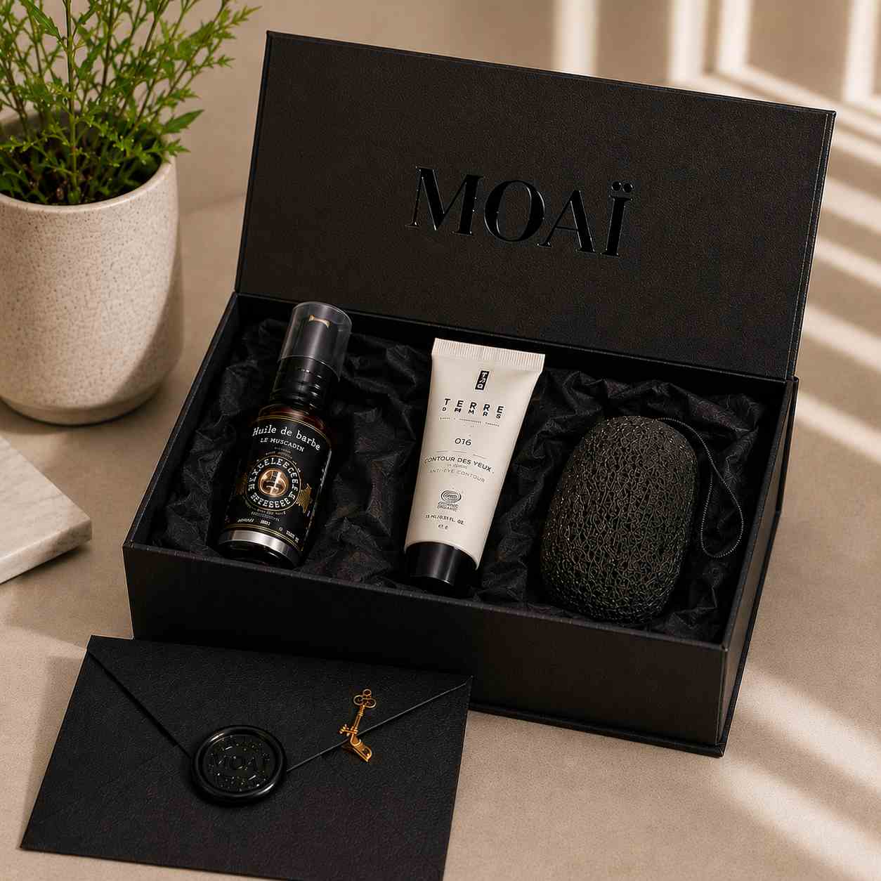 Coffret de soins homme MOAÏ ouvert contenant deux soins visage et un accessoire exfoliant, présentés dans un écrin noir élégant. Une enveloppe cachetée accompagnée d’une clé dorée complète cette sélection premium prête à offrir.