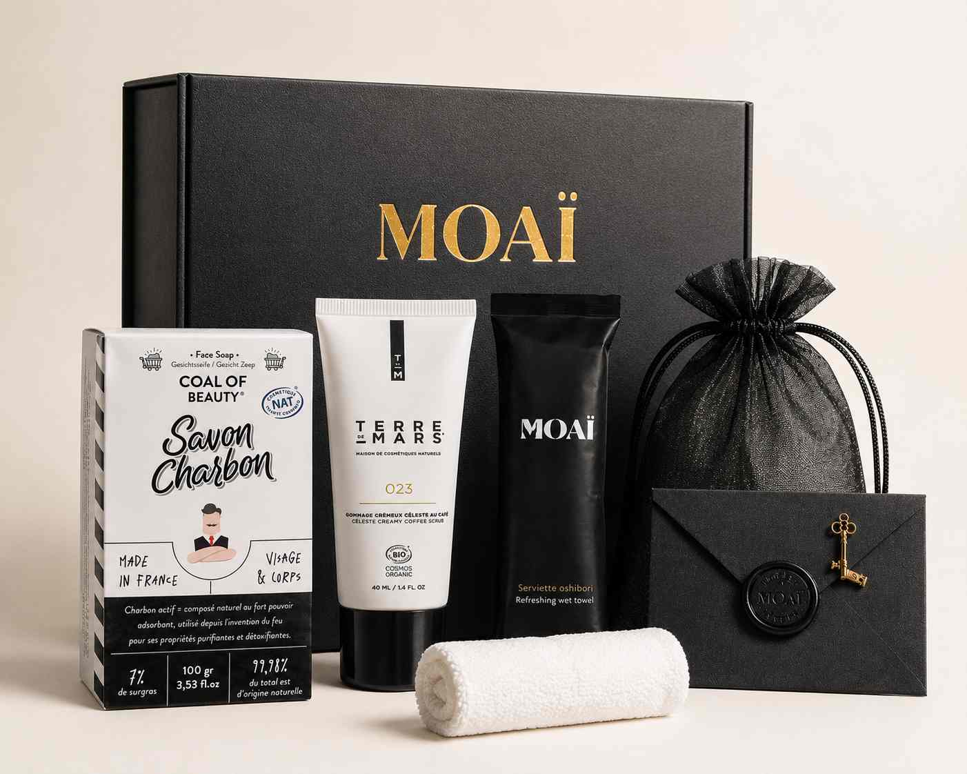 Coffret cadeau MOAÏ pour homme entouré de ses produits de soin : un savon au charbon Coal of Beauty, un gommage Terre de Mars, un oshibori et un pochon noir.