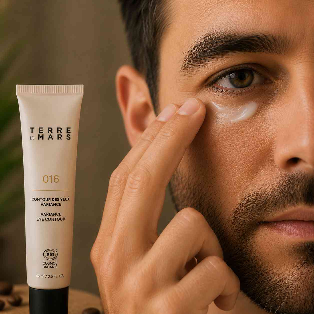 Homme appliquant le contour des yeux au café Terre de Mars. Soin bio qui réduit l'apparence des cernes et des poches, lisse les ridules et défatigue le regard.