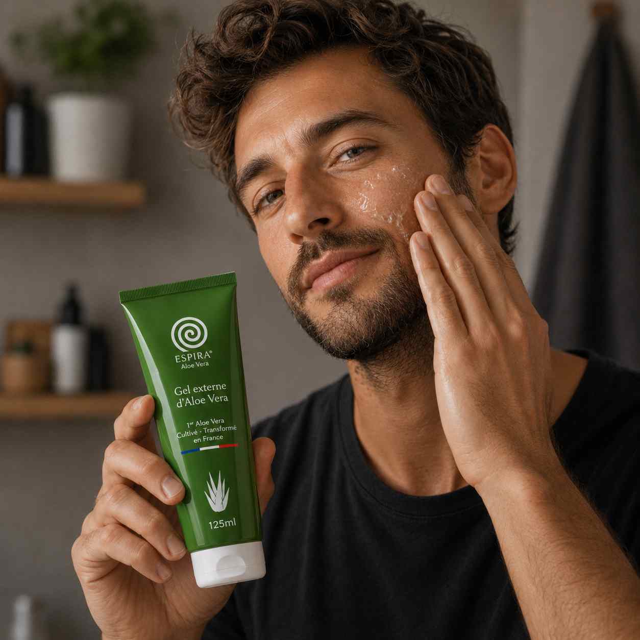 Homme souriant appliquant du gel d'aloe vera sur sa joue tout en tenant un tube de Gel Externe d’Aloe Vera de la marque Espira.