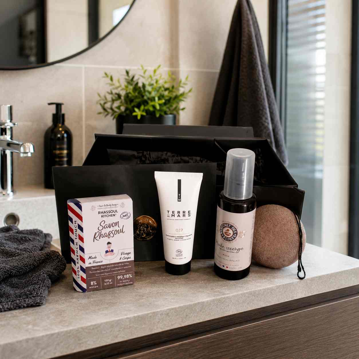 Assortiment de soins pour homme posé sur un meuble de salle de bain à côté d'une box noire.