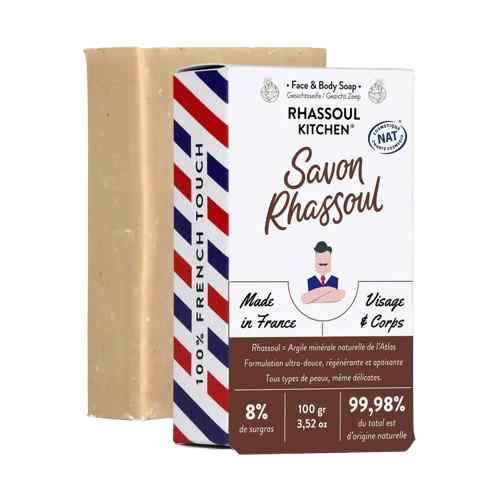 Pain de savon solide au rhassoul posé derrière son emballage cartonné blanc et bleu de la marque Rhassoul Kitchen.