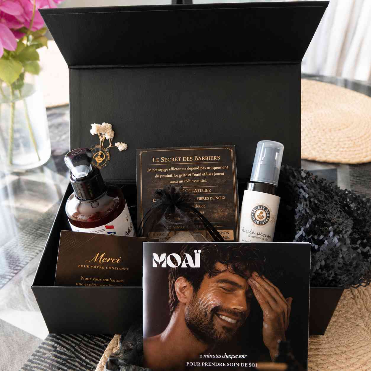 Unboxing du coffret cadeau homme MOAÏ comprenant un nettoyant visage exfoliant, une huile de noisette, des accessoires premium et un guide de soins.